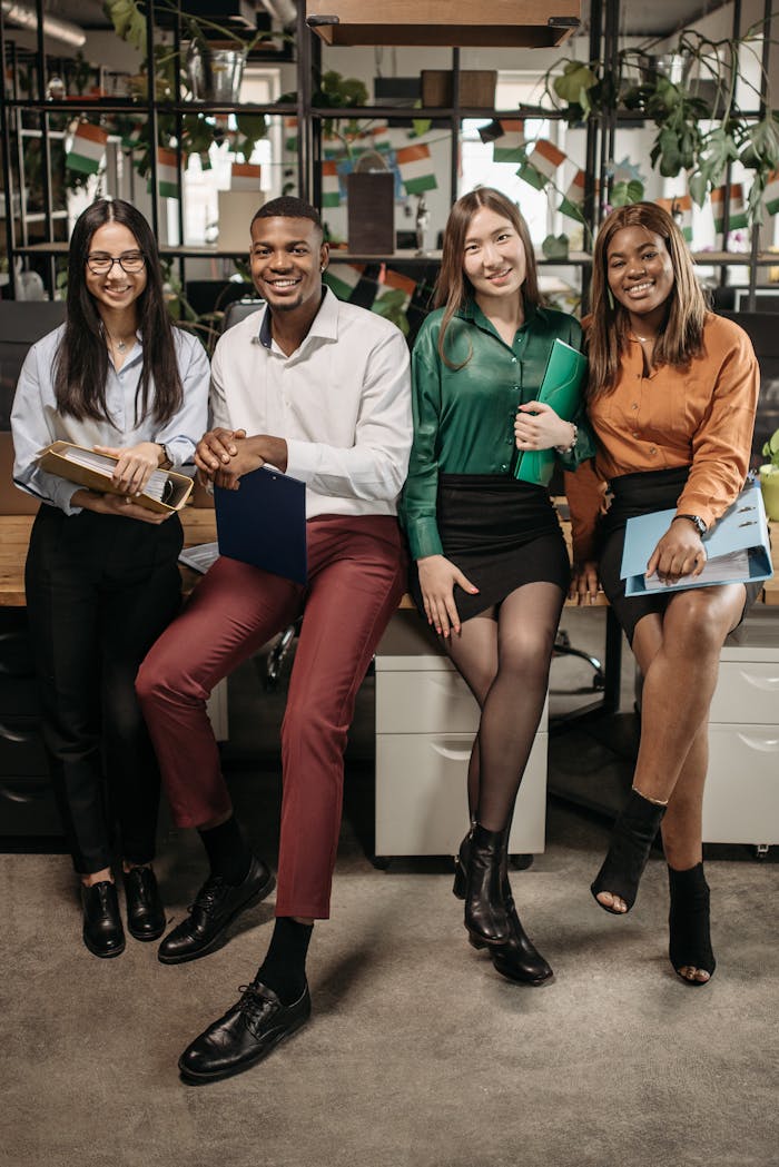 A diverse group of young professionals posing and smiling in a modern office setting.
